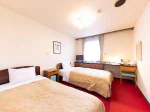 a hotel room with two beds and a desk at Tabist Business Hotel Takizawa Takasaki Station Nishiguchi in Takasaki