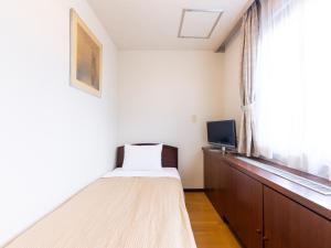 a small bedroom with a bed and a window at Tabist Business Hotel Takizawa Takasaki Station Nishiguchi in Takasaki