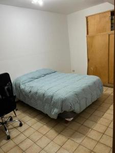een slaapkamer met een bed en een stoel erin bij Departamento Garibaldi 239 in Mendoza