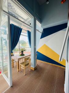 a dining room with a table and a blue and yellow wall at The Blue House in Da Lat