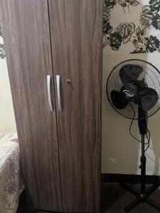 um armário de madeira com uma ventoinha ao lado de uma cama em hostel 148 em Petrópolis