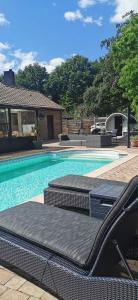 a swimming pool with two lounge chairs next to a house at B&B Woodside in Torhout