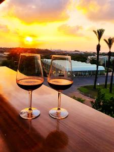 dos copas de vino sentadas en una mesa con la puesta de sol en Rose Suite en Caesarea