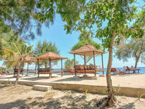 a group of benches and umbrellas on the beach at Nusa Indah Bungalows in Gili Air