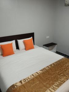 een slaapkamer met een groot wit bed met oranje kussens bij One World Hotel in Kulai