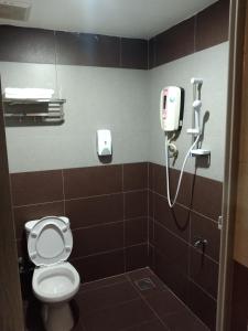 a bathroom with a toilet and a phone on the wall at One World Hotel in Kulai
