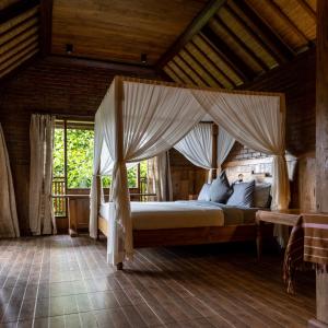 a bedroom with a bed with a canopy at Nienté Bali in Penebel