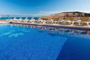 a group of chairs sitting next to a swimming pool at Hotel Monopol in Puerto de la Cruz