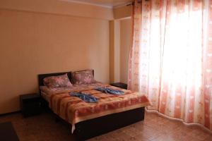 a bedroom with a bed and a window with a curtain at Adilet Fatima in Bishkek