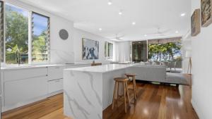 a white kitchen with a large island and a living room at Walk To Beach! in Palm Cove