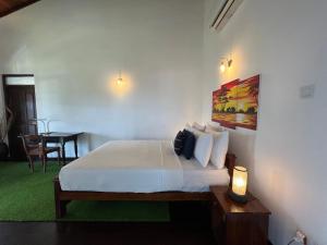 um quarto com uma cama e uma mesa com um candeeiro em Lahiru Villa em Galle