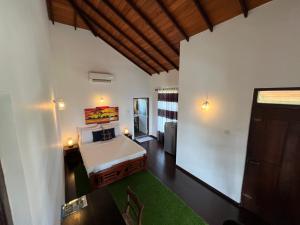 a bedroom with a white bed and a green rug at Lahiru Villa in Galle