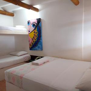 a bedroom with two beds and a painting on the wall at Caramba Hospedaje in Tonsupa
