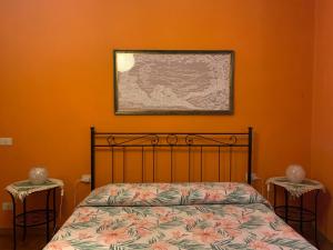 a bedroom with an orange wall with a bed and two tables at Appartamento il Leone in Empoli