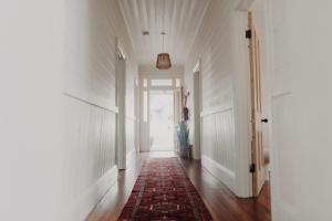 un pasillo con una alfombra roja en el suelo y una puerta en The Allotment Albany - Centrally Located Cottage in Old Albany, en Albany