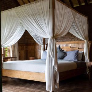 a bedroom with a canopy bed with white curtains at Nienté Bali in Penebel