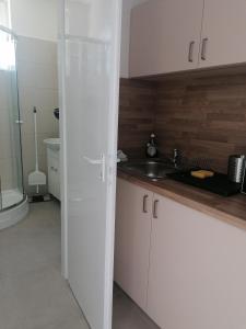 a kitchen with white cabinets and a sink and a toilet at Sóstói Strand Apartmanház in Siófok +30 photos