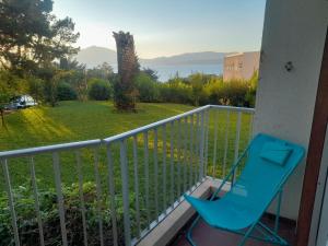 a blue chair on a balcony with a view of a yard at PORTICCIO BRILOC APPART DUPLEX à 150m de la plage. in Porticcio
