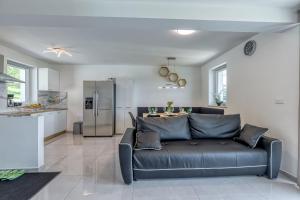 a living room with a black couch and a kitchen at Pool & Whirlpool Art Villas in Trebnje