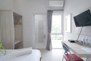 Jest to biały pokój z łóżkiem, biurkiem i oknem. w obiekcie Urbanview Hotel Bari Syariah Palembang By RedDoorz w mieście Sukarami