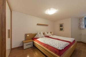 a bedroom with a large bed with a red blanket at Ottohof - Feldblick in Colle Isarco