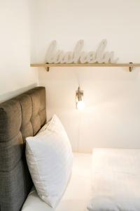 un sofá con una almohada blanca y un cartel en la pared en R&R Residenzen Ferienwohnungen en Mitterbach