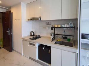 a small kitchen with white cabinets and a stove at Cozy Studio @Skyhouse BSD in Samporo