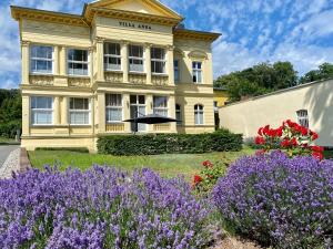 un bâtiment jaune avec des fleurs violettes devant lui dans l'établissement Villa Anna - Johann Strauss, à Heringsdorf