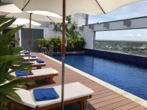 a hotel pool with chairs and umbrellas on a building at V V Hotel Battambang in Battambang
