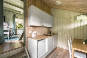 a kitchen with white cabinets and a table and a dining room at Gilė -'Virš Ąžuolų' - Forest SPA - Horses - Lake - Chalet in Paplatelė