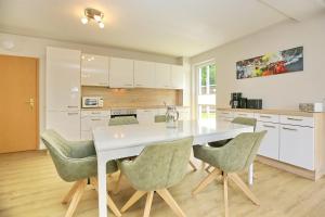 a kitchen with a white table and green chairs at Strandvilla Krabbe Wohnung 15 in Boltenhagen