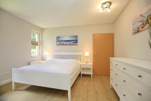 a bedroom with a white bed and a dresser at Strandvilla Krabbe Wohnung 15 in Boltenhagen
