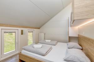 two beds in a room with two windows at Pool & Whirlpool Art Villas in Trebnje