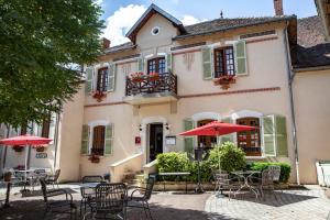 a building with tables and chairs and red umbrellas at Hostellerie du Chateau Bellenaves in Bellenaves