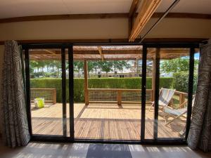 un porche cubierto con una puerta corredera de cristal en Chalet panoramique avec vue sur étang, en Bec-de-Mortagne