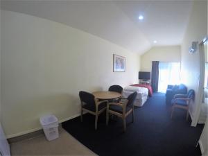 a hotel room with a bed and a table and chairs at The Peaks Motor Inn in Ohakune
