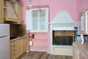 una cucina con pareti rosa e un camino di Casa Sofia sul Lago Trasimeno a Torricella