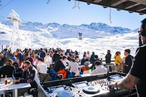 a large crowd of people sitting at tables on a ski slope at Fahrenheit Seven Val Thorens in Val Thorens