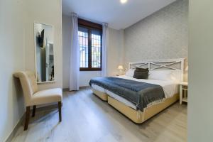 ein Schlafzimmer mit Bett, Stuhl und Schreibtisch in der Unterkunft Holidays2Malaga Suites in Málaga