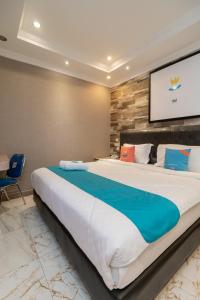 1 cama grande en una habitación de hotel con TV en Sans Hotel Beauty Palembang, en Sukarami