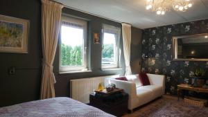 ein Schlafzimmer mit einem weißen Stuhl und einem Fenster in der Unterkunft B&B aan het bos in Ter Apel