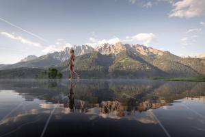 a woman standing on the water with mountains in the background at Apartments Hermann's in San Candido