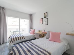 2 Betten in einem Zimmer mit einem Tisch und einem Fenster in der Unterkunft LuxuryFlats La Isleta - 2BR - Balcony - Parking - Beach in Las Palmas de Gran Canaria