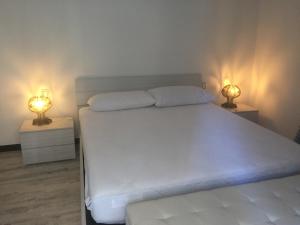 een slaapkamer met een wit bed met twee lampen bij ca Debora Apartment in Rapallo