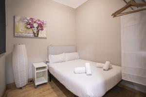 a small bedroom with a white bed and a vase of flowers at 23PAR1007 Comfortable apartment in Paralel in Barcelona