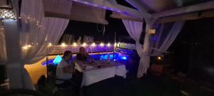 Una pareja sentada en una mesa en una fiesta por la noche en Casa de madera luz de Carlota en La Solana