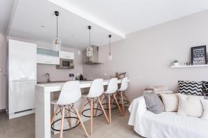 cocina blanca con sillas blancas y encimera de cocina en Appartement Le Patio - Stationnement privatif & Tram - proche Montpellier en Saint-Jean-de-Védas