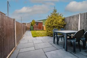 a patio with a table and chairs and a fence at Newly refurbished Modern Stylish 2 Bedroom Cottage in Lowestoft
