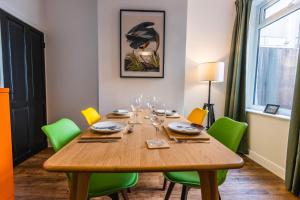 a dining room table with green chairs and a wooden table at Newly refurbished Modern Stylish 2 Bedroom Cottage in Lowestoft