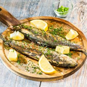 two fish on a wooden plate with cheese and lemon slices at Casa de la ghiol in Murighiol